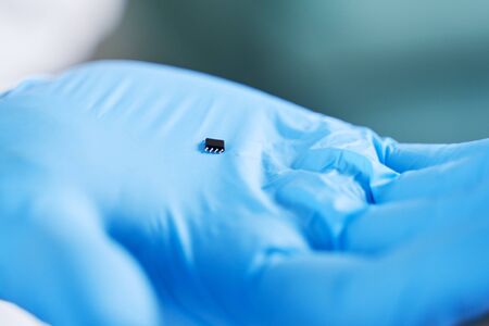 Hand holds chip compenent. Embedding the chip under human skin, microcontroller implanting NFC technology.の写真素材