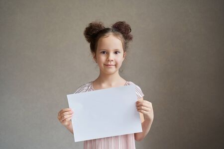 a beautiful girl with two tails holds a white piece of paper for writing.の写真素材