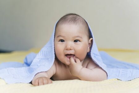 Newborn Asian cute boy is lying on the bed under a blanket.の写真素材