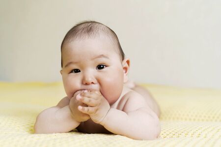 Newborn Asian cute boy holding hands in his mouth. teethingの写真素材