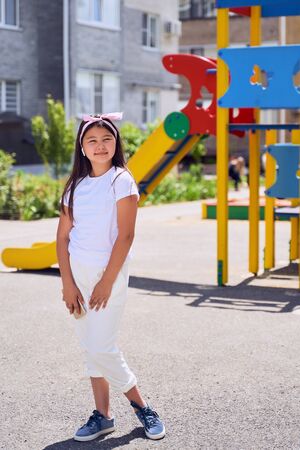 beautiful little Asian girl with black hair in white clothes on the Playground.の写真素材
