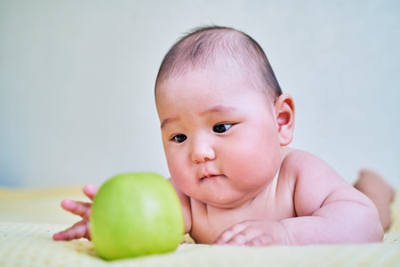 funny Asian kid and green Apple. healthy food for babies.