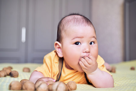 funny Asian kid chewing on a walnut. teething.
