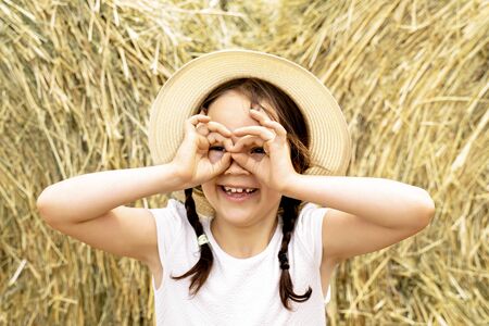 beautiful cheerful girl in a straw hat on the hay.の写真素材