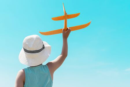 a child with a plane against the blue sky. rear view.の写真素材
