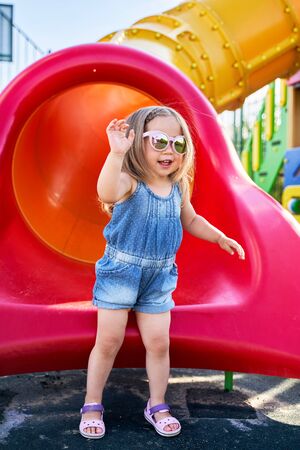 little girl in sunglasses on the Playground in summer.の写真素材