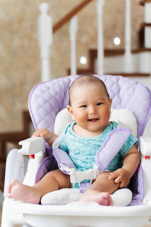 beautiful Asian six-month-old boy sitting in a child seat.の写真素材