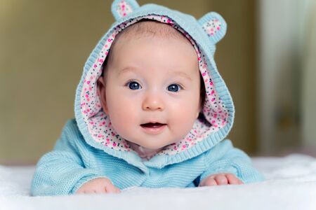 a beautiful newborn blue eyed girl lies on her tummy and smiles.の写真素材