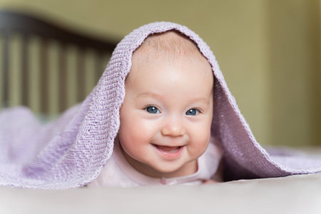 a beautiful newborn blue eyed girl lies on her tummy and smiles.