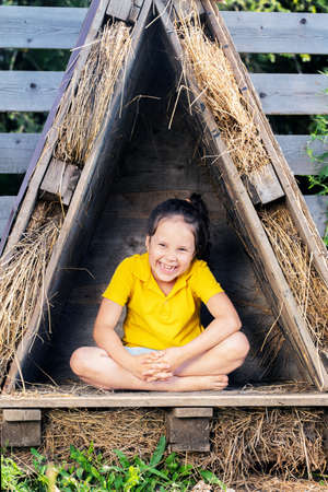 a girl in a bright yellow t-shirt sits in a small hut.の写真素材