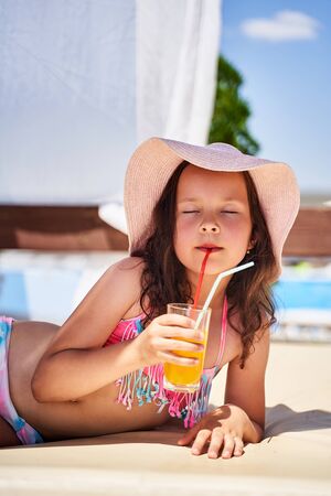 the girl lies on the beach and drinks juice with pleasure.の写真素材