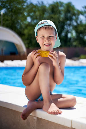 boy on the beach eating corn on the beach.の写真素材