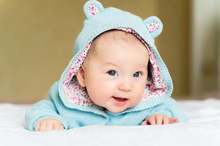 a beautiful newborn blue eyed girl lies on her tummy and smiles.の写真素材