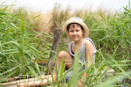 a little boy in a hat is fishing in the reedsの写真素材