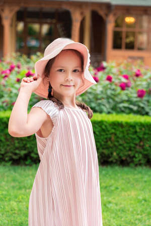 a beautiful little girl in a hat stands stands and looks at the camera.の写真素材
