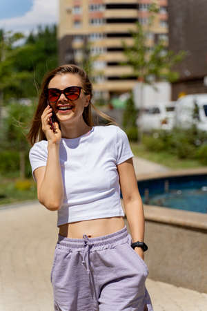 athletic girl in a short top on the street talking on the phone.の写真素材