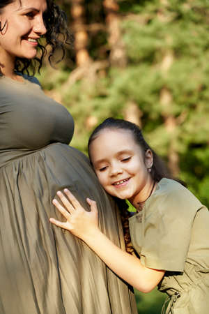 the daughter hugs the pregnant mother and waits for the appearance of her sister.の写真素材