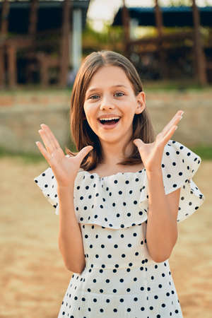 a little girl on the beach in a polka dot dress laughs and puts her hands out to the sideの写真素材