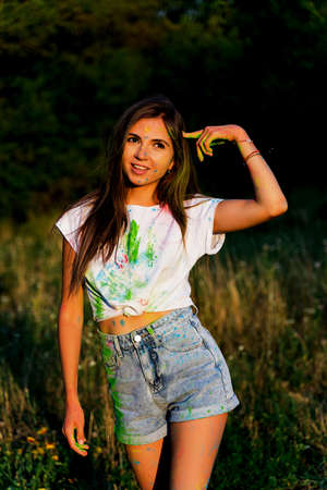 a young funny girl smeared with paint holds a finger to her head.の写真素材