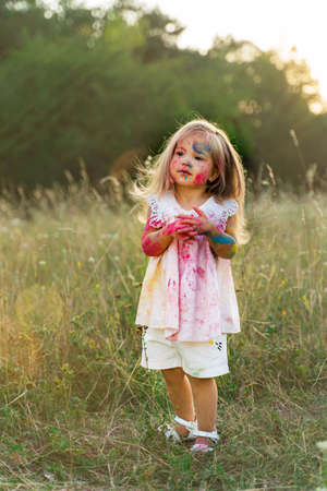 the little girl was covered in paint. a girl in a green clearing. hair upの写真素材