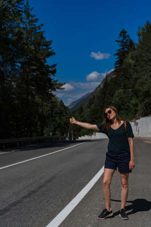 Active healthy girl tourist catches a car on the road.の写真素材
