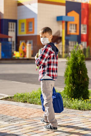 a small schoolboy in a medical mask goes to schoolの写真素材