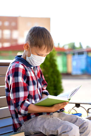 A small child in a mask with a school bag during an outbreak of the virus going to school or kindergarten.の写真素材