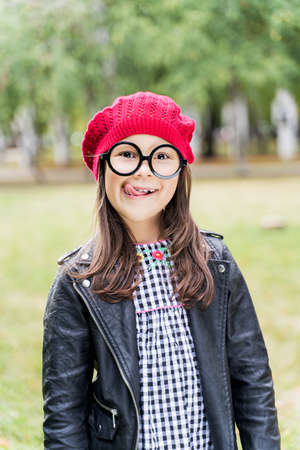 a little girl in a red cap shows her tongue playfully.の写真素材