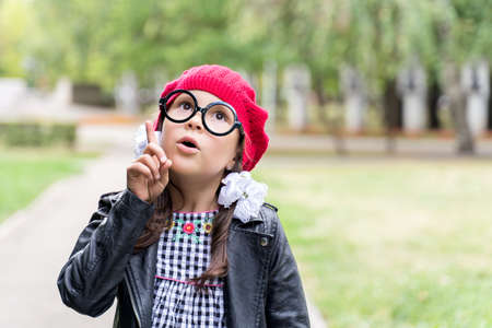 a funny little girl in a red cap holds up her finger. I got an ideaの写真素材