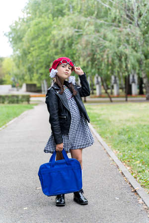 a little funny girl in a red cap and a briefcase goes to schoolの写真素材