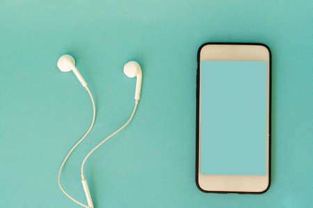 the smartphone and headphones are on a blue backgroundの写真素材
