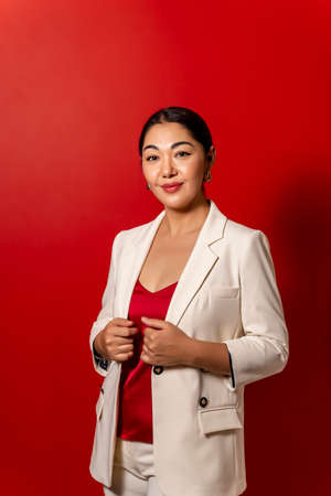 beautiful business Asian girl in white jacket on red backgroundの写真素材