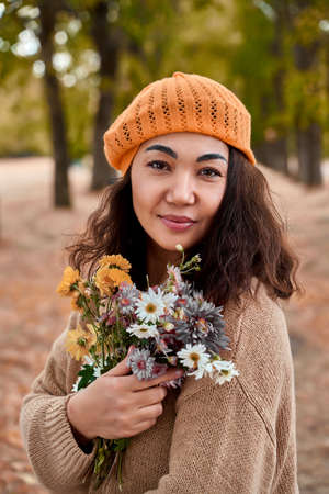 gorgeous Asian girl with wildflowers in yellow beret in autumn Park.の写真素材