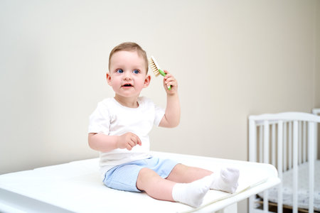 a small child with blue eyes holds a comb in his handsの写真素材