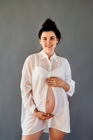 beautiful pregnant girl in a shirt with a bare stomach.の写真素材