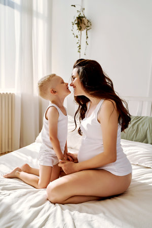 a little son and his pregnant mother are lying on the bed.の写真素材