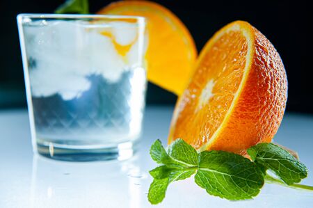 Fresh lemonade with mint, orange and ice in glass jar on the dark blue background. Summer cold drink and cocktailの写真素材