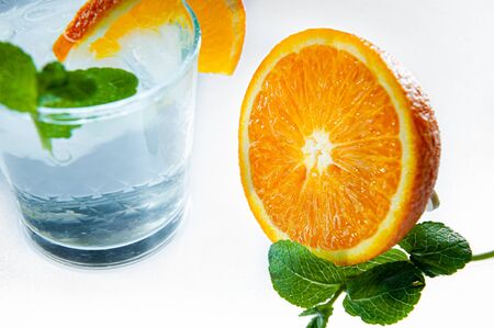 Fresh lemonade with mint, orange and ice in glass jar on the light background. Summer cold drink and cocktailの写真素材