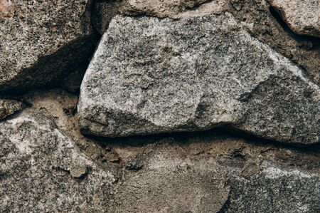 Dark Aged Shabby Cliff Face And Divided By Huge Cracks And Layers. Coarse, Rough Gray Stone Or Rock Texture Of Mountains, Background And Copy Spaceの写真素材