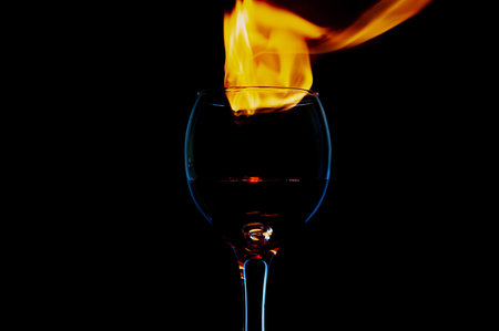 glass with wine on fire and flame on a black background insulationの写真素材
