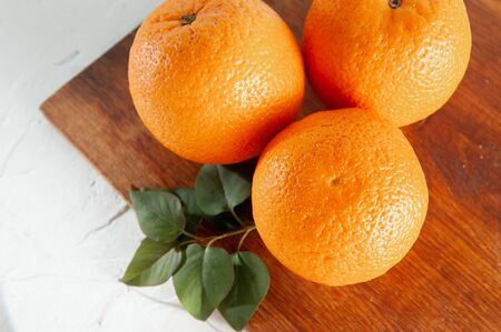 whole oranges on a wooden board on a white background with green leaves, top viewの写真素材