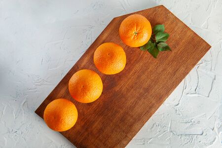 whole oranges on a wooden board on a white background with green leaves, top viewの写真素材