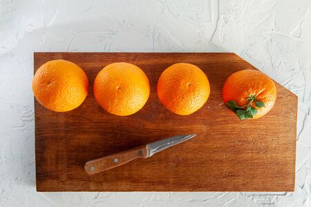 whole oranges on a wooden board on a white background with green leaves, top viewの写真素材