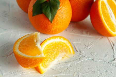 whole and slices of orange with green leaves on a light texture view from above. Close-up and flat-layの写真素材