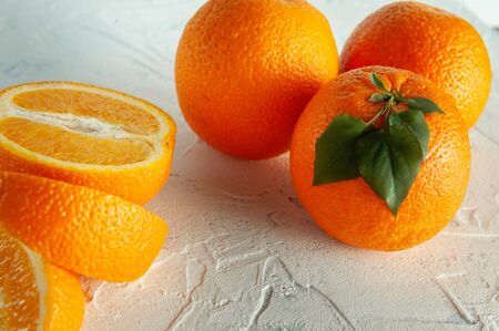 whole and slices of orange with green leaves on a light texture view from above. Close-up and flat-layの写真素材