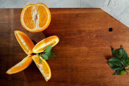 orange slices lie on a wooden board with green leaves. Top view and close-upの写真素材