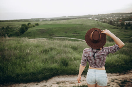 Girl admiring the views standing in the field in a cowboy hat there is an empty space for...