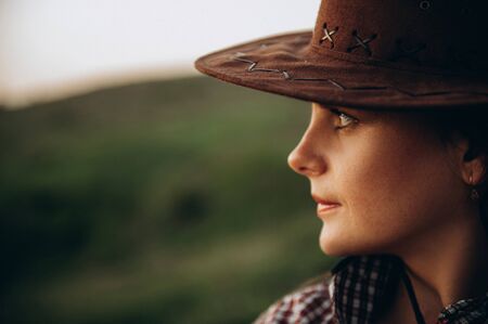 Girl in cowboy hat looks at sunset there is an empty space to write textの写真素材