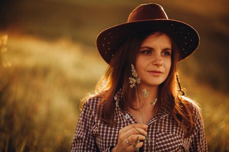Girl in American country style, shirt and cowboy hat at nature On the Sunset. Girl from Texas styleの写真素材
