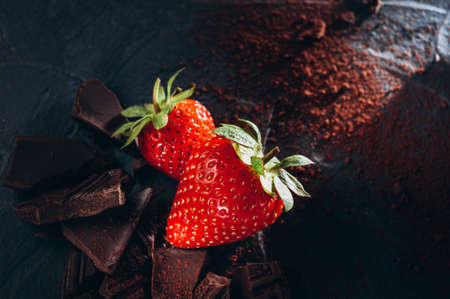 A few strawberries with chocolate and cocoa on a dark backgroundの写真素材